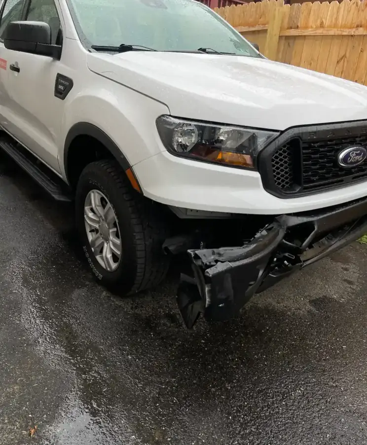 White Ford Ranger with front-end collision damage to the bumper before repair