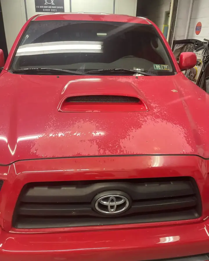 Red Toyota Tacoma with peeling clear coat on the hood, in the shop for paint restoration in Lansdowne, PA